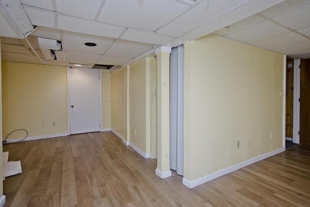 basement with a drop ceiling and light wood-type flooring