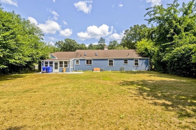 rear view of house featuring a sunroom and a lawn