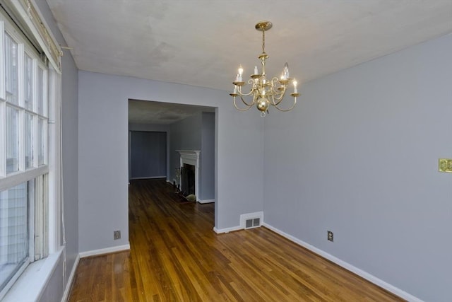 unfurnished dining area featuring dark hardwood / wood-style flooring and a chandelier