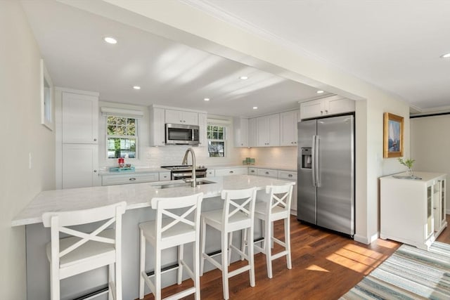 21 Glenwood St, Yarmouth, MA 02673 - kitchen featuring appliances with stainless steel finishes, dark wood-type flooring, a breakfast bar area, decorative backsplash, and recessed lighting