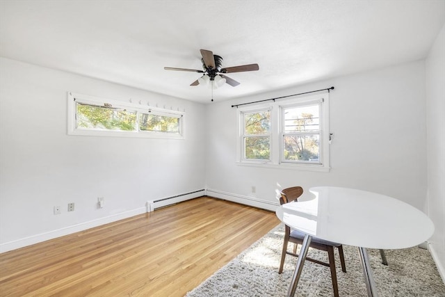 office space featuring light wood finished floors, a baseboard radiator, a ceiling fan, and baseboards