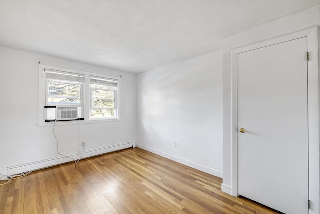 spare room with a baseboard radiator, cooling unit, light wood-style flooring, and baseboards