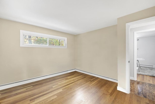 unfurnished room featuring a baseboard heating unit and wood finished floors