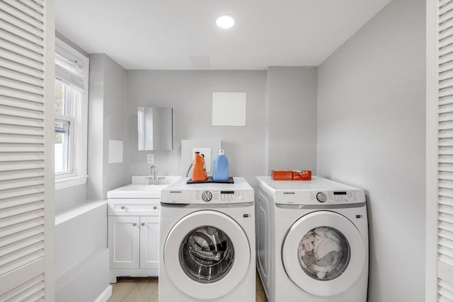 laundry area featuring recessed lighting, separate washer and dryer, a sink, cabinet space, and light wood finished floors