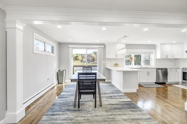 dining area featuring baseboard heating, plenty of natural light, wood finished floors, and baseboards