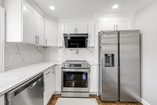 kitchen with light stone countertops, appliances with stainless steel finishes, white cabinets, and backsplash