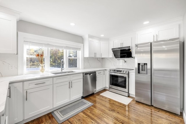 kitchen with stainless steel appliances, white cabinetry, a sink, and wood finished floors