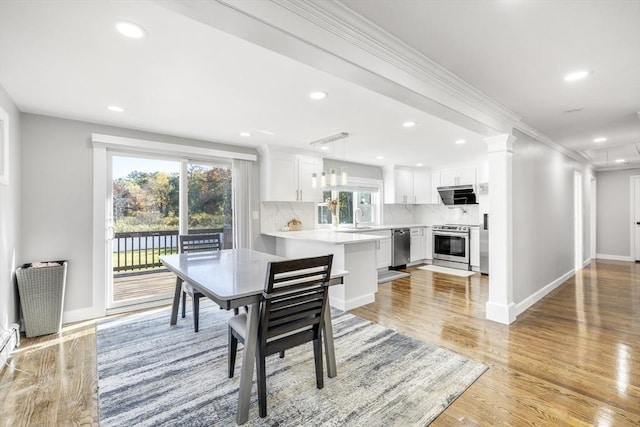 dining space featuring decorative columns, baseboards, ornamental molding, light wood-style floors, and recessed lighting