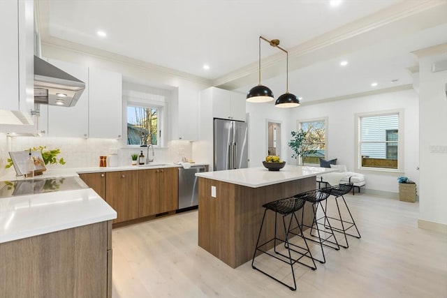 kitchen with decorative light fixtures, a center island, white cabinetry, and stainless steel appliances