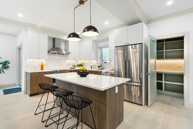 kitchen featuring a center island, white cabinets, wall chimney range hood, and appliances with stainless steel finishes