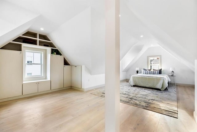 bedroom featuring light wood-type flooring, vaulted ceiling, and multiple windows