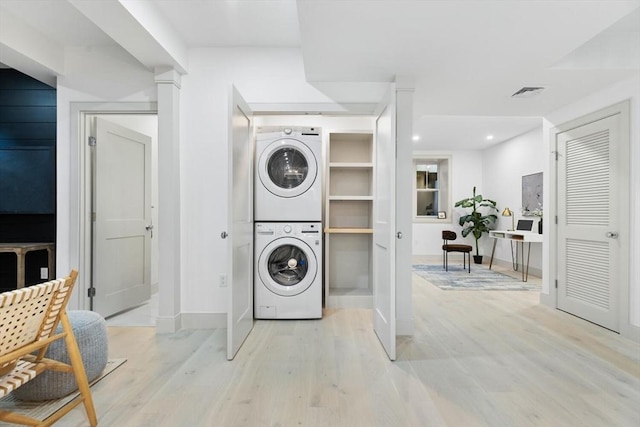 washroom with stacked washing maching and dryer and light hardwood / wood-style floors