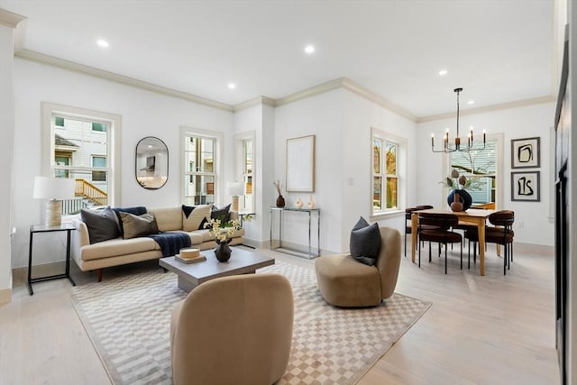 living room featuring a chandelier, light wood-type flooring, crown molding, and a healthy amount of sunlight