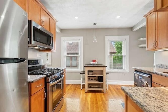 29 Daniels St Unit 29, Arlington, MA 02476 - kitchen featuring stainless steel appliances, light wood finished floors, brown cabinets, light stone counters, and recessed lighting