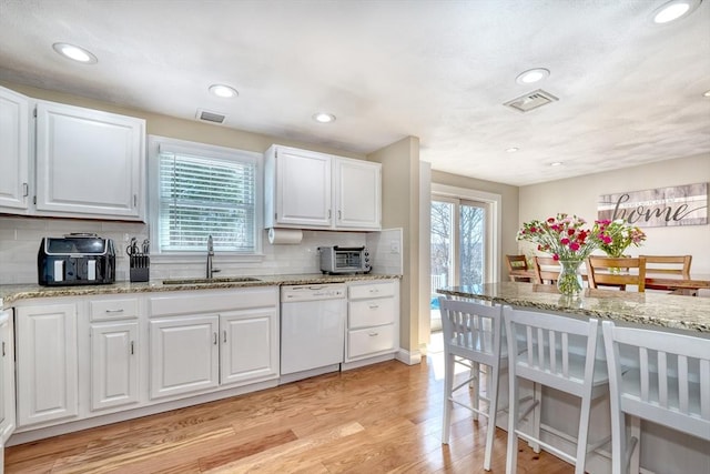 kitchen featuring dishwasher, light wood-type flooring, visible vents, and a sink