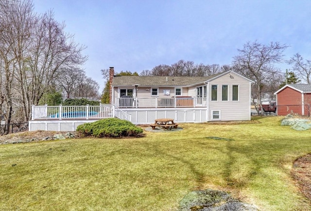 back of house featuring a lawn, a deck, and a chimney