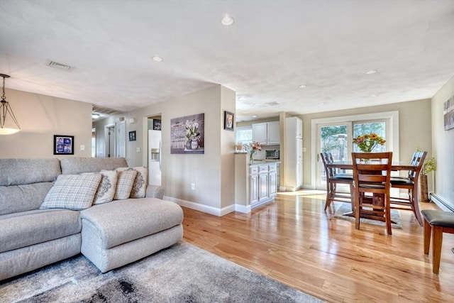 living room featuring recessed lighting, light wood-style flooring, visible vents, and baseboards