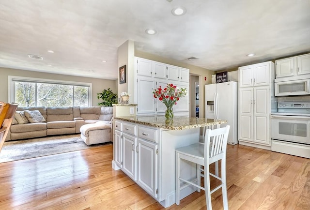 kitchen with visible vents, light wood-type flooring, light stone counters, white appliances, and white cabinets