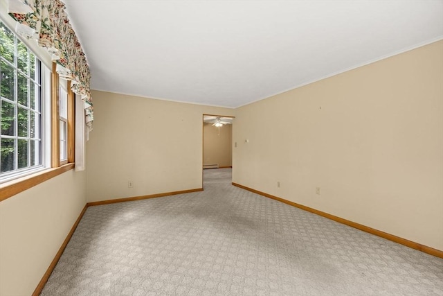 empty room with light carpet, plenty of natural light, a baseboard radiator, and baseboards