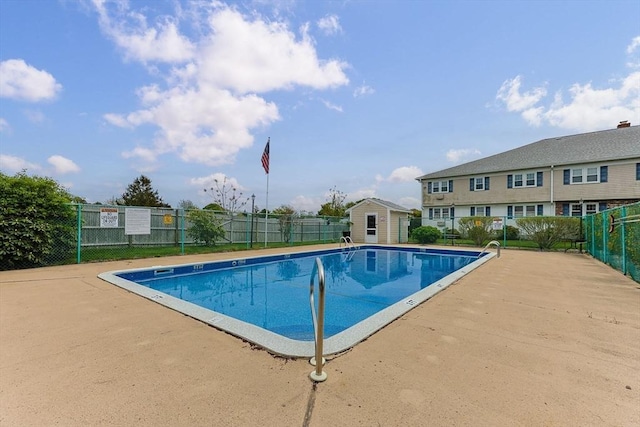 community pool with fence, an outbuilding, and a storage unit