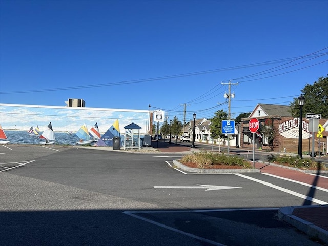view of asphalt road featuring traffic signs, curbs, street lighting, and sidewalks