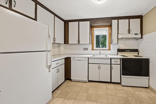 kitchen featuring white appliances, a sink, under cabinet range hood, light countertops, and decorative backsplash