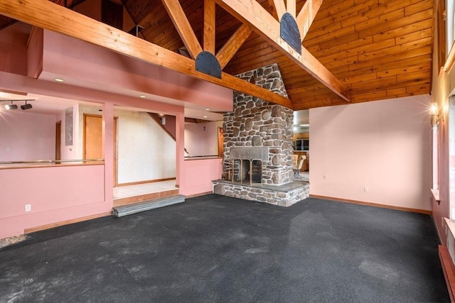 unfurnished living room featuring beamed ceiling, baseboards, high vaulted ceiling, and a stone fireplace