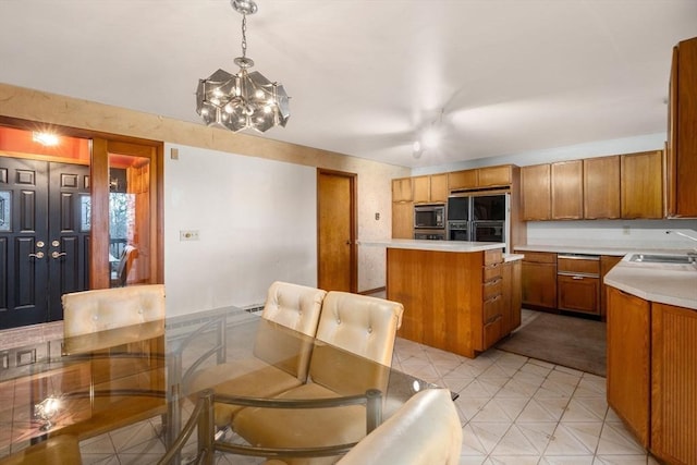 kitchen featuring an inviting chandelier, brown cabinets, black appliances, and light countertops