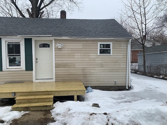 exterior space with roof with shingles, a chimney, and fence