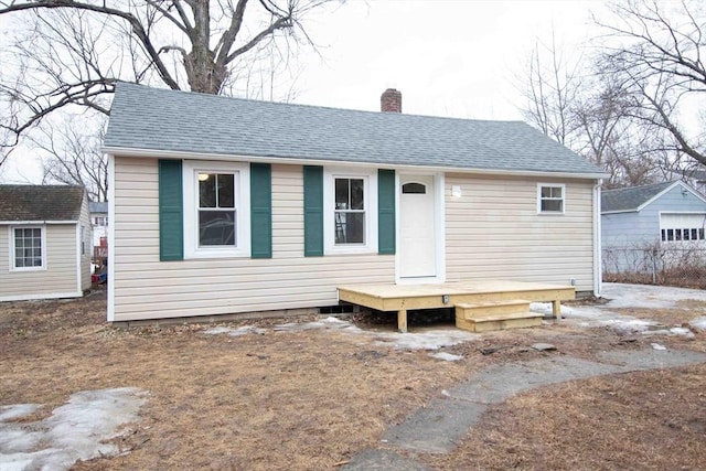 bungalow with a chimney, an outbuilding, and roof with shingles