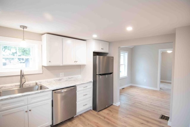 kitchen with visible vents, light wood-style flooring, stainless steel appliances, white cabinetry, and a sink