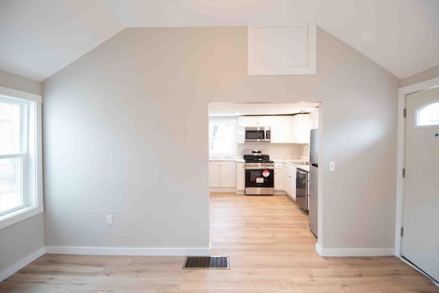 kitchen with stainless steel appliances, white cabinetry, vaulted ceiling, and visible vents