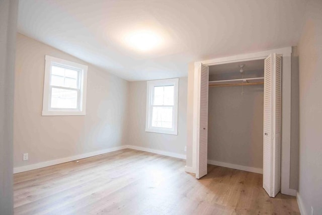 unfurnished bedroom with a closet, baseboards, vaulted ceiling, and wood finished floors