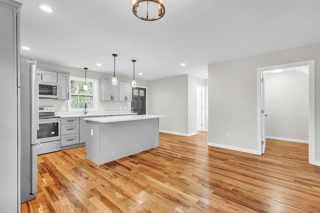 kitchen with a center island, pendant lighting, gray cabinets, appliances with stainless steel finishes, and light hardwood / wood-style floors