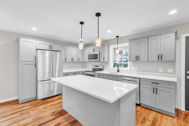 kitchen featuring a kitchen island, sink, pendant lighting, light hardwood / wood-style floors, and stainless steel appliances