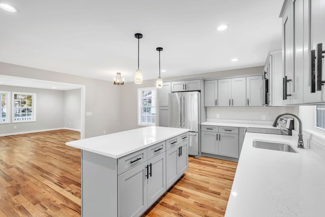 kitchen featuring light hardwood / wood-style floors, stainless steel fridge, sink, and gray cabinetry