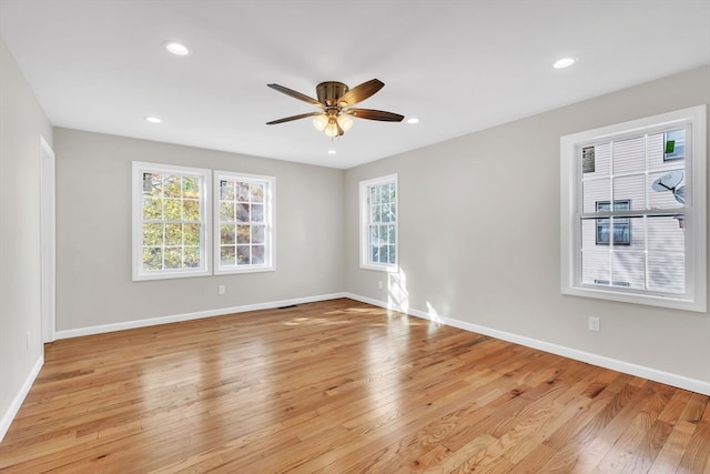 empty room with a wealth of natural light, light hardwood / wood-style floors, and ceiling fan