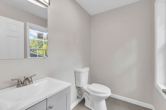 bathroom with toilet, hardwood / wood-style flooring, and vanity