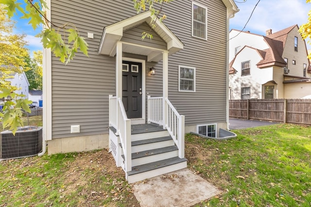 doorway to property featuring a lawn and cooling unit