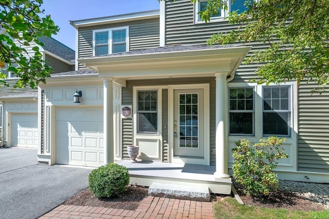 doorway to property featuring a porch, a garage, and aphalt driveway