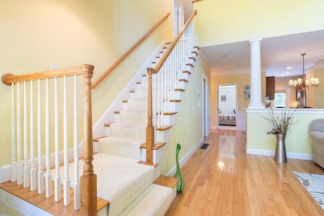 stairway featuring decorative columns, wood-type flooring, baseboards, and ornamental molding