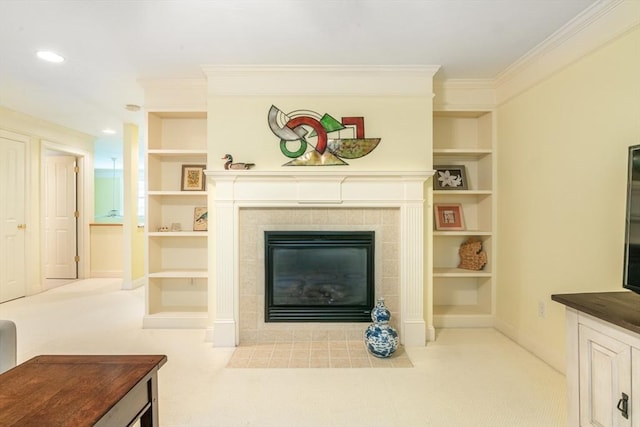 carpeted living room featuring built in features, a tiled fireplace, ornamental molding, and baseboards