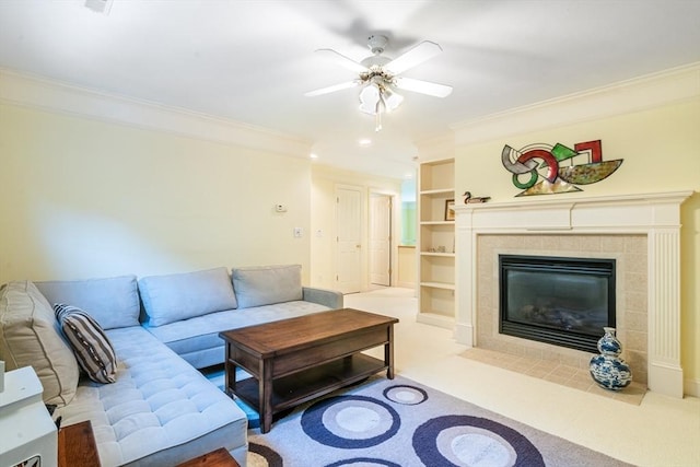 living room with a tile fireplace, a ceiling fan, crown molding, and carpet floors