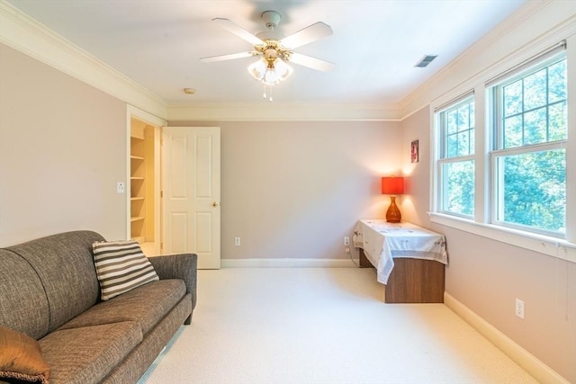 living area with crown molding, ceiling fan, baseboards, and carpet