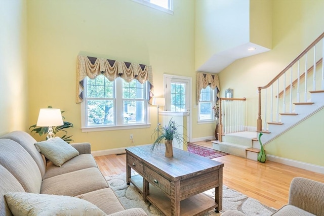 living area with stairway, a high ceiling, baseboards, and wood finished floors