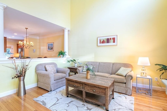 living area featuring crown molding, baseboards, ornate columns, and hardwood / wood-style floors