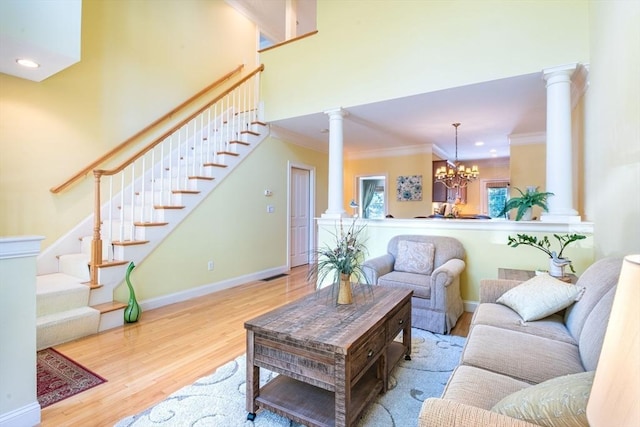 living area with decorative columns, ornamental molding, stairway, wood finished floors, and baseboards