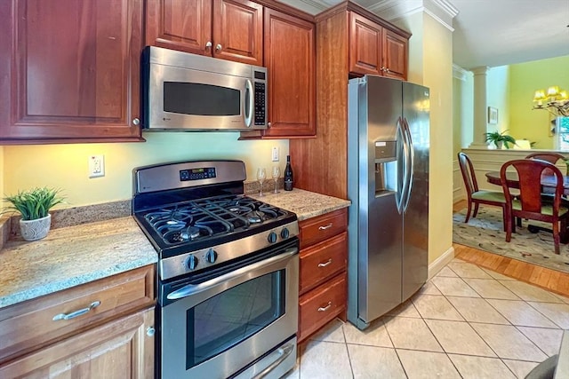 kitchen with appliances with stainless steel finishes, light tile patterned floors, an inviting chandelier, and light stone countertops
