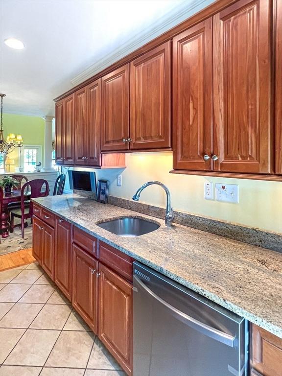 kitchen with a notable chandelier, light stone counters, light tile patterned flooring, stainless steel dishwasher, and a sink