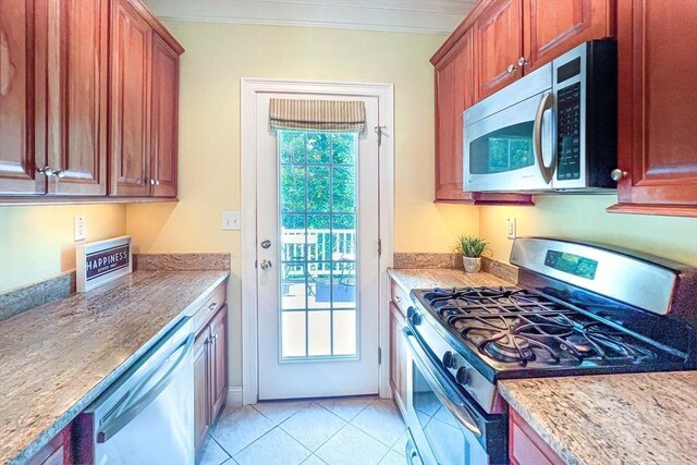 kitchen featuring stainless steel appliances, light tile patterned floors, crown molding, and light stone counters
